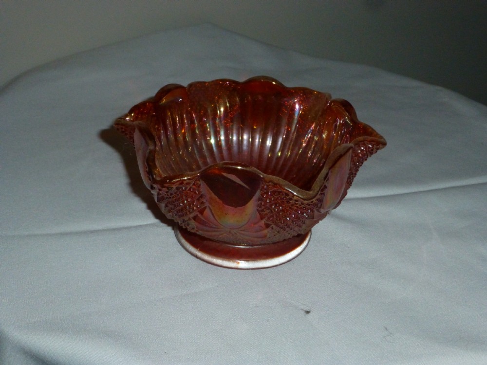 An amber iridescent carnival glass bowl with raised diamond press patterning and a scalloped rim. View II