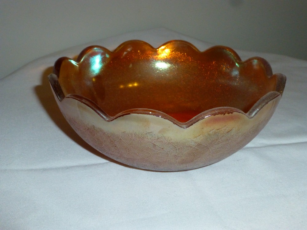 An amber carnival glass bowl featuring a scalloped rim and a metallic iridescent sheen with a textured exterior.