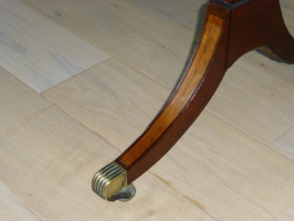 A Regency mahogany drop-leaf sofa table featuring two drawers with dark round knobs, splayed legs ending in brass castors, and a turned central stretcher. View III