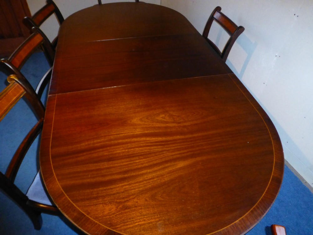 A Regency style mahogany extending dining table with twin pillar pedestal legs, surrounded by six matching mahogany chairs with light grey upholstered seats. View II
