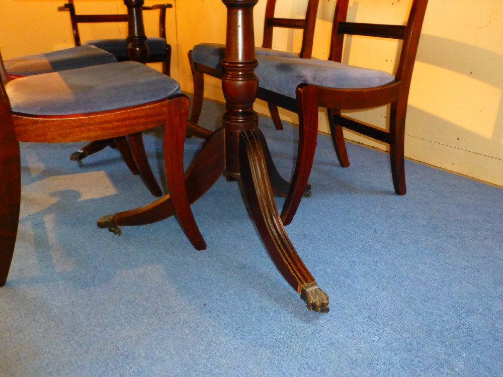 A Regency style mahogany extending dining table with twin pillar pedestal legs, surrounded by six matching mahogany chairs with light grey upholstered seats. View III
