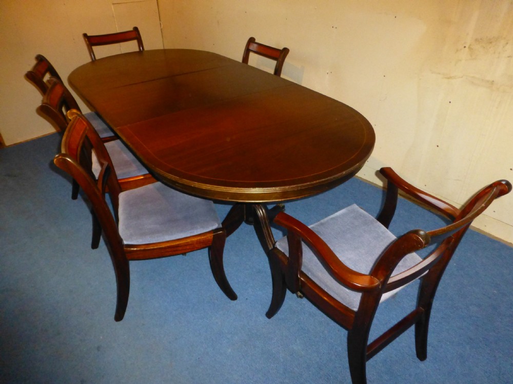 A Regency style mahogany extending dining table with twin pillar pedestal legs, surrounded by six matching mahogany chairs with light grey upholstered seats. View V
