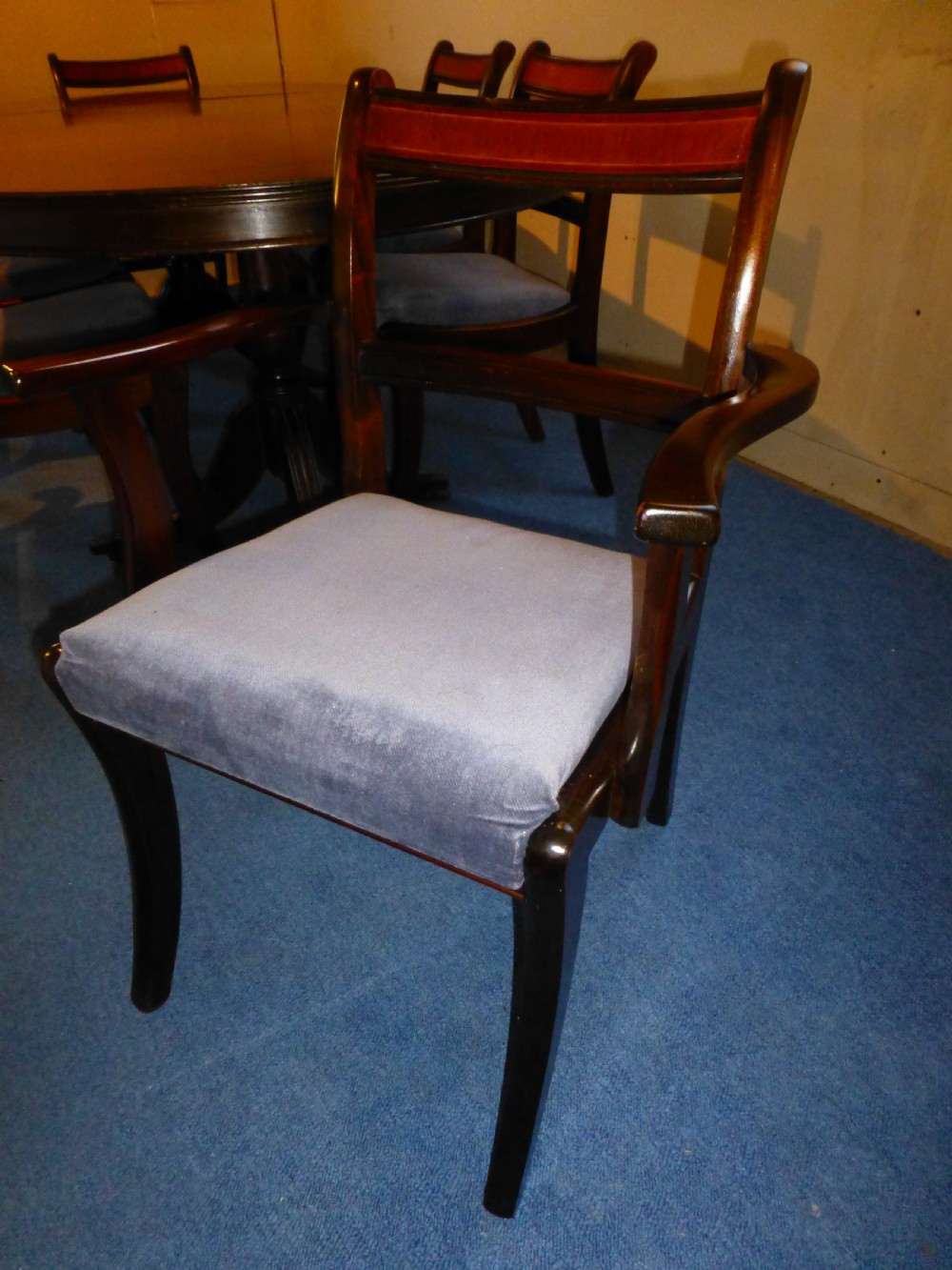 A Regency style mahogany extending dining table with twin pillar pedestal legs, surrounded by six matching mahogany chairs with light grey upholstered seats. View VI