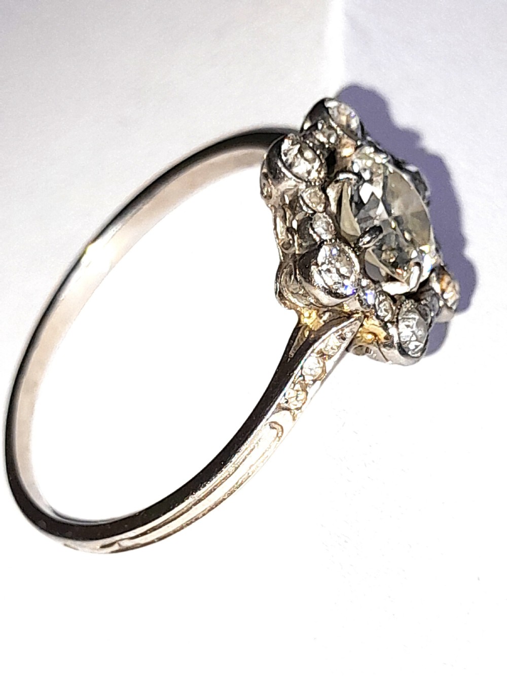An Edwardian platinum ring featuring a central round diamond encircled by a hexagonal halo of smaller diamonds with milgrain borders. View II