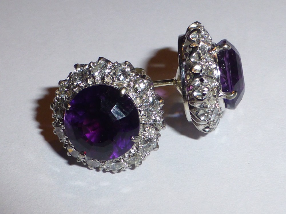A pair of round white gold stud earrings featuring central purple amethysts encircled by brilliant-cut diamonds. View II