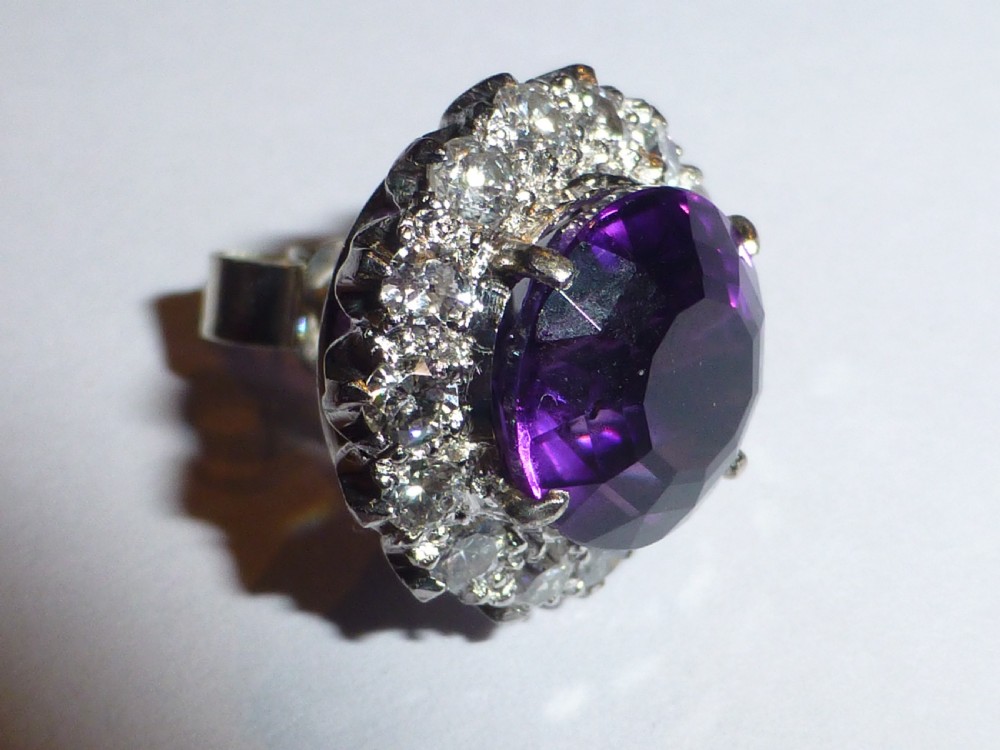 A pair of round white gold stud earrings featuring central purple amethysts encircled by brilliant-cut diamonds. View III