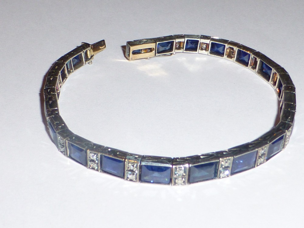 An Art Deco line bracelet featuring rectangular blue sapphires alternating with pairs of small diamonds in white metal.
