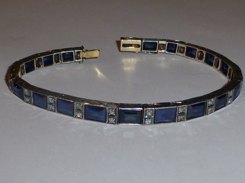 An Art Deco line bracelet featuring rectangular blue sapphires alternating with pairs of small diamonds in white metal. View II