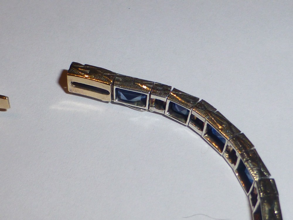 An Art Deco line bracelet featuring rectangular blue sapphires alternating with pairs of small diamonds in white metal. View III