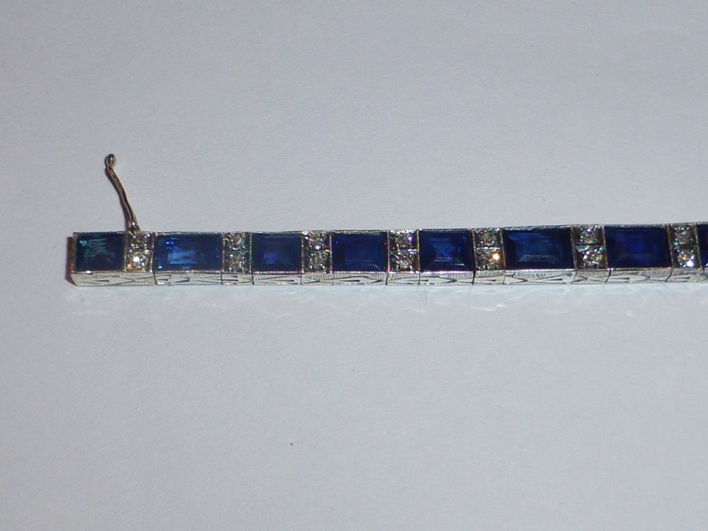 An Art Deco line bracelet featuring rectangular blue sapphires alternating with pairs of small diamonds in white metal. View IV