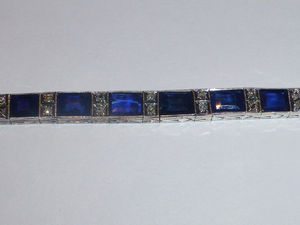 An Art Deco line bracelet featuring rectangular blue sapphires alternating with pairs of small diamonds in white metal. View V