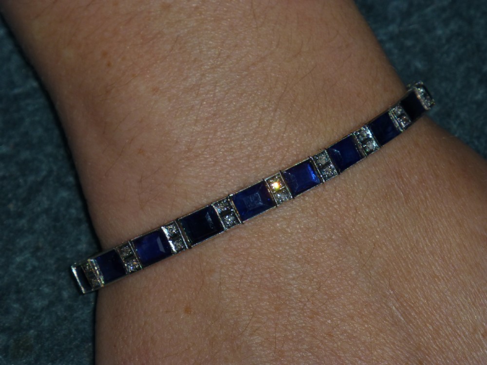 An Art Deco line bracelet featuring rectangular blue sapphires alternating with pairs of small diamonds in white metal. View VII