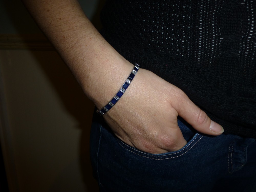 An Art Deco line bracelet featuring rectangular blue sapphires alternating with pairs of small diamonds in white metal. View VIII