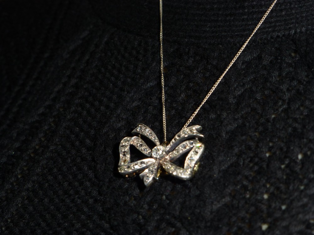 A nineteenth-century bow-shaped brooch set with diamonds in silver-topped gold, featuring a central round diamond and a pin fitting on the reverse. View VII