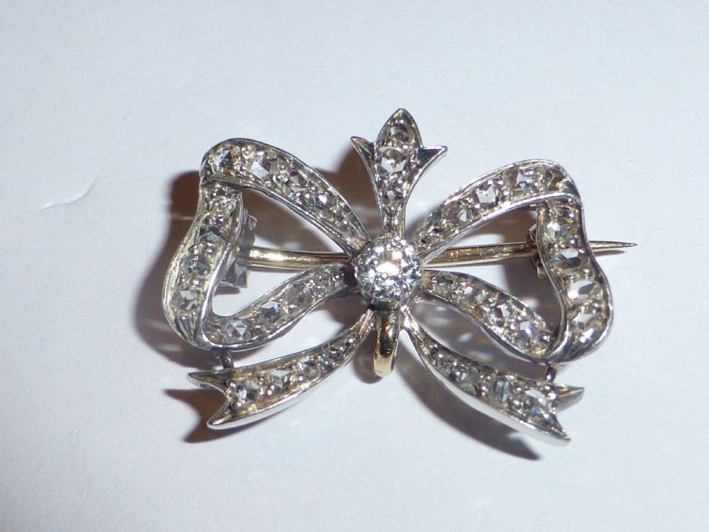 A nineteenth-century bow-shaped brooch set with diamonds in silver-topped gold, featuring a central round diamond and a pin fitting on the reverse. View XII