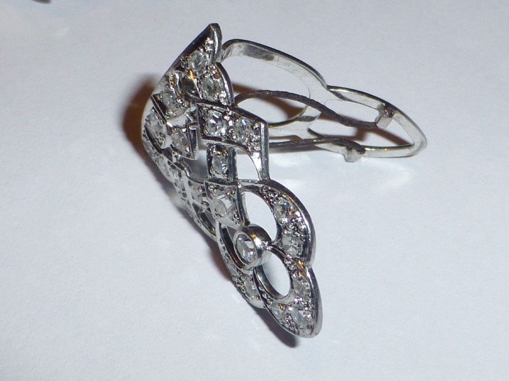 An Art Deco platinum and diamond double clip brooch featuring intricate geometric openwork set with round diamonds. View V