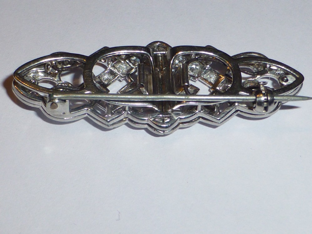An Art Deco platinum and diamond double clip brooch featuring intricate geometric openwork set with round diamonds. View VII