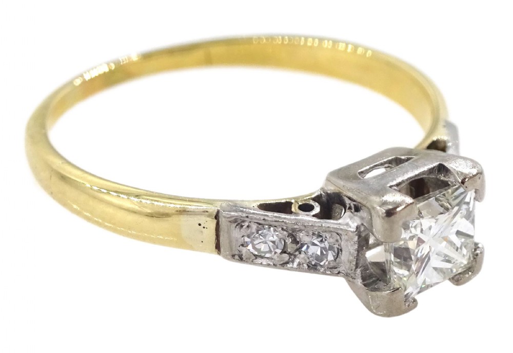 A two-tone yellow gold and platinum engagement ring featuring a central square-cut diamond set in claws with accent diamonds along the shoulders.