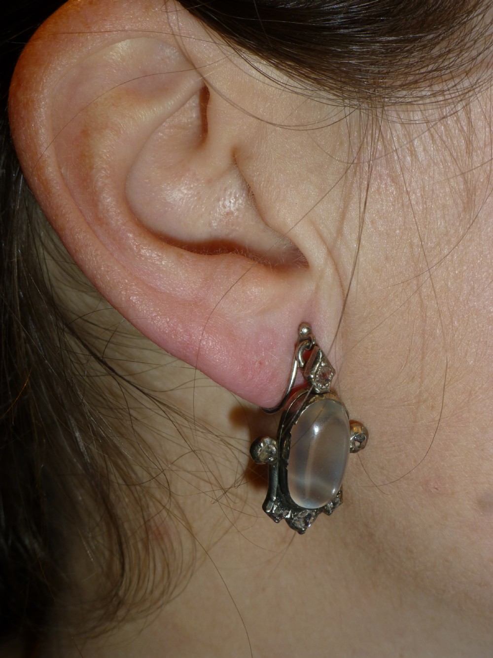 A pair of antique Georgian silver drop earrings featuring central oval cabochon moonstones surrounded by small rose-cut diamonds. View II