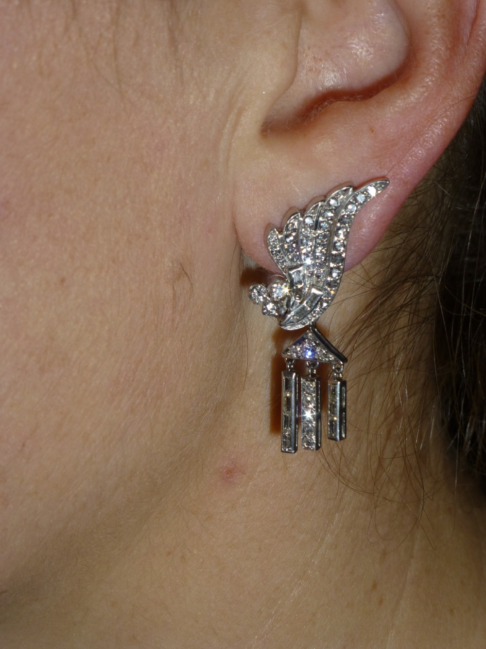 A pair of Art Deco platinum earrings set with round and baguette diamonds, featuring winged tops and detachable geometric drop pendants. View V
