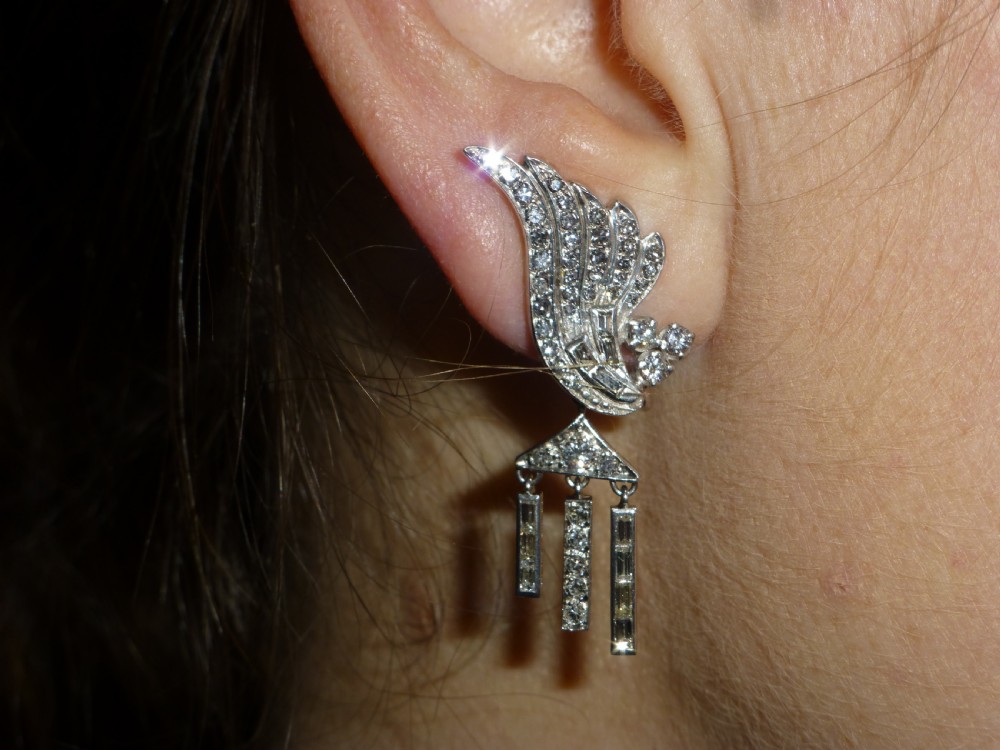 A pair of Art Deco platinum earrings set with round and baguette diamonds, featuring winged tops and detachable geometric drop pendants. View VI