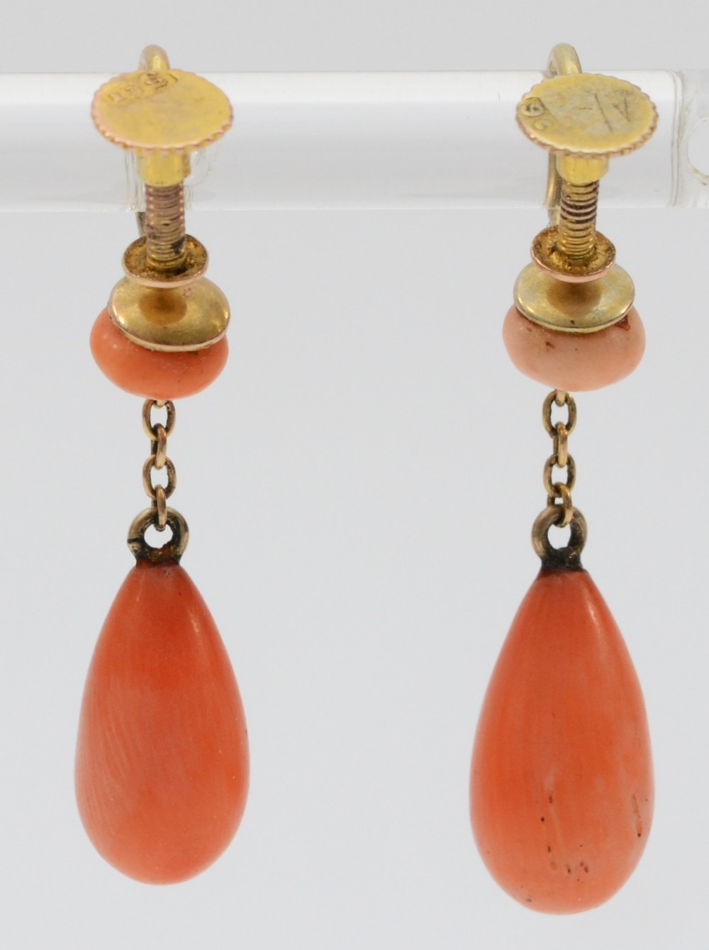 A pair of Victorian gold drop earrings featuring smooth teardrop-shaped coral pendants suspended from fine gold chains and screw-back fittings.