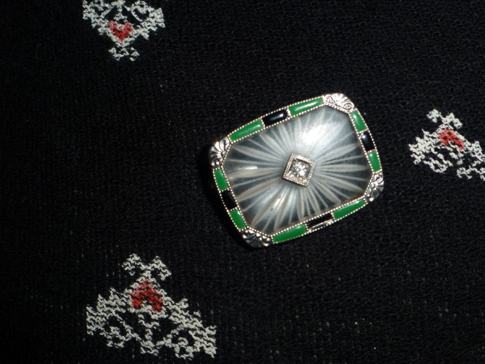An Art Deco rectangular white gold brooch featuring a starburst-carved translucent rock crystal quartz plaque set with a central diamond, surrounded by green chrysoprase and black onyx inlays. View II