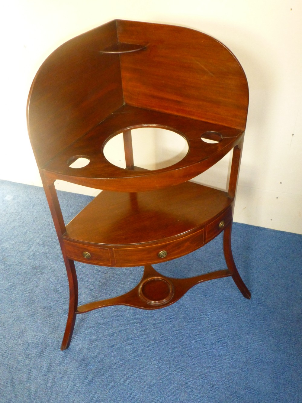 An 18th-century Georgian mahogany corner washstand featuring a curved splashback, a top tier with basin aperture, a lower shelf with a drawer, and curved legs. View II