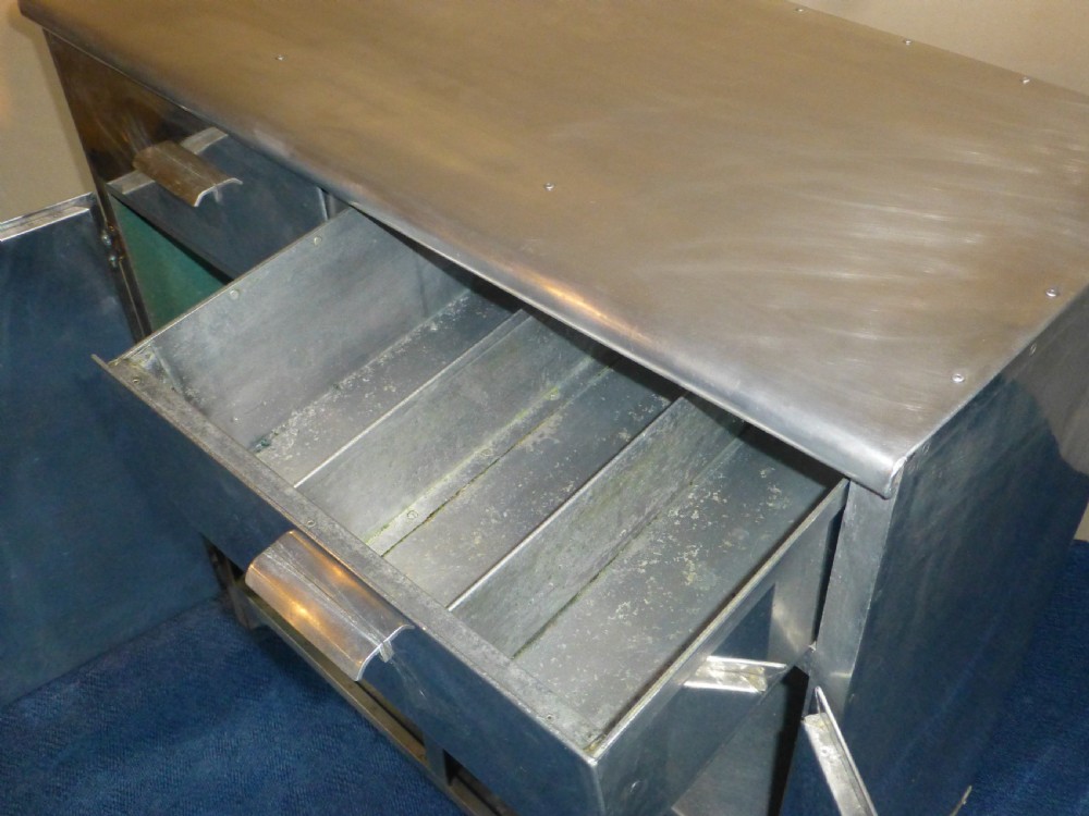 An aluminium metal sideboard featuring two upper drawers, two lower cabinet doors, riveted joinery, and exposed metal hinges. View VII
