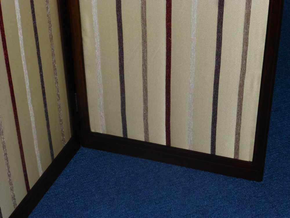 An Edwardian three-panel mahogany folding screen featuring arched top rails and cream striped fabric inserts. View V