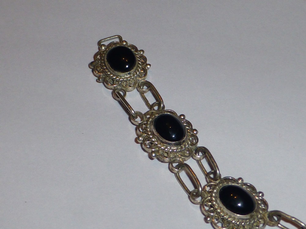 A silver link bracelet featuring oval black onyx cabochons held within pierced filigree frames. View II