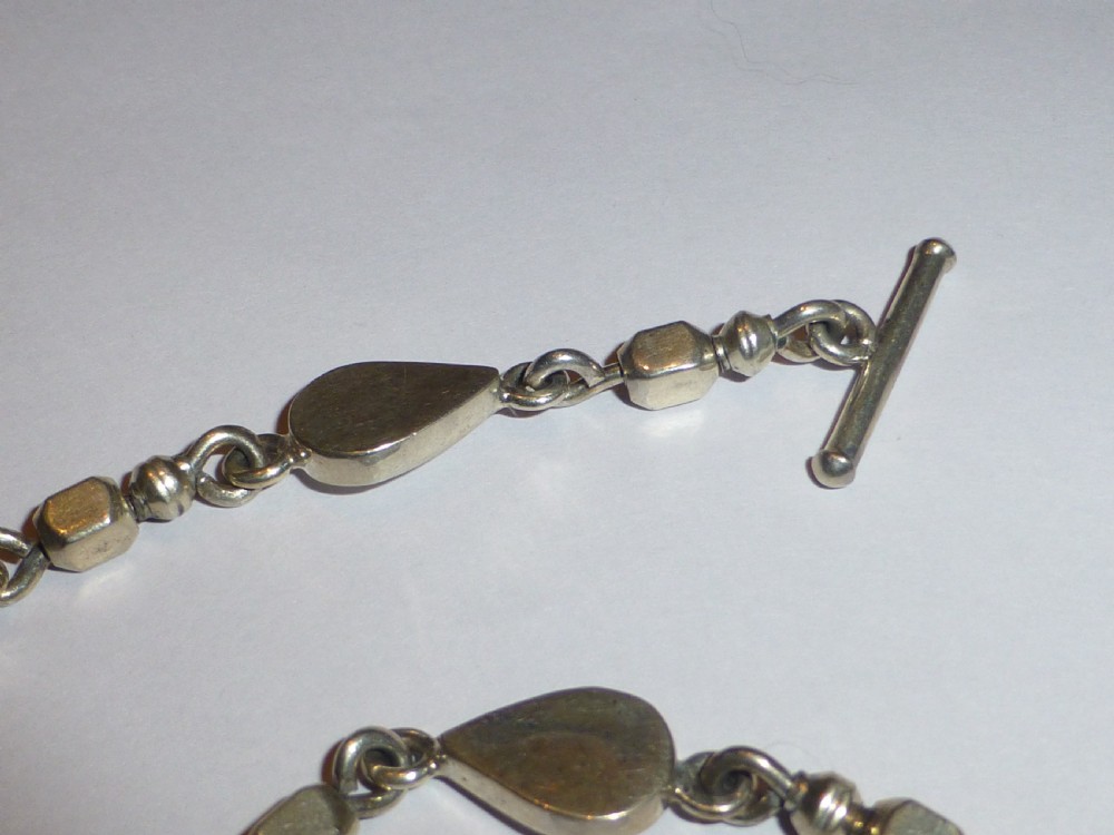 A vintage sterling silver link necklace featuring repeating teardrop motifs and small silver bead spacers secured with a toggle clasp. View II