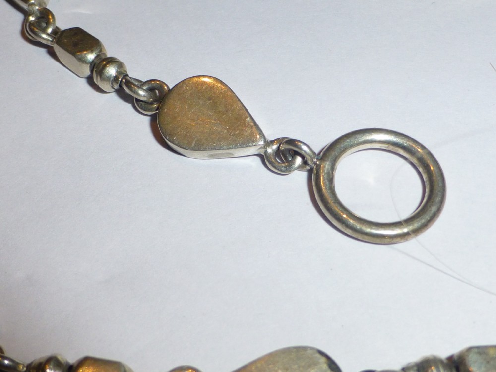 A vintage sterling silver link necklace featuring repeating teardrop motifs and small silver bead spacers secured with a toggle clasp. View III