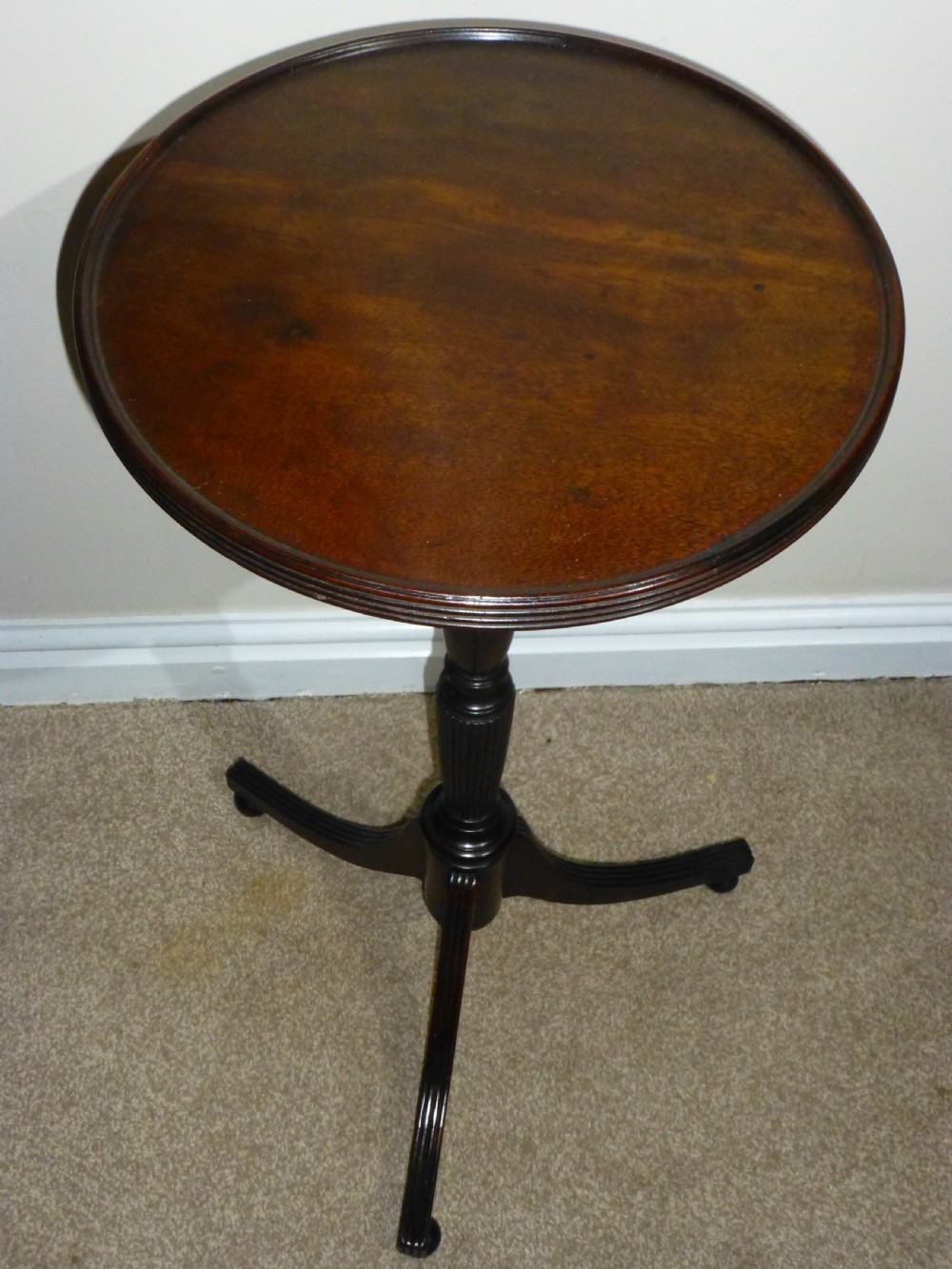 A Regency mahogany circular wine table featuring a moulded rim, a turned reeded pedestal, and three swept tripod legs.