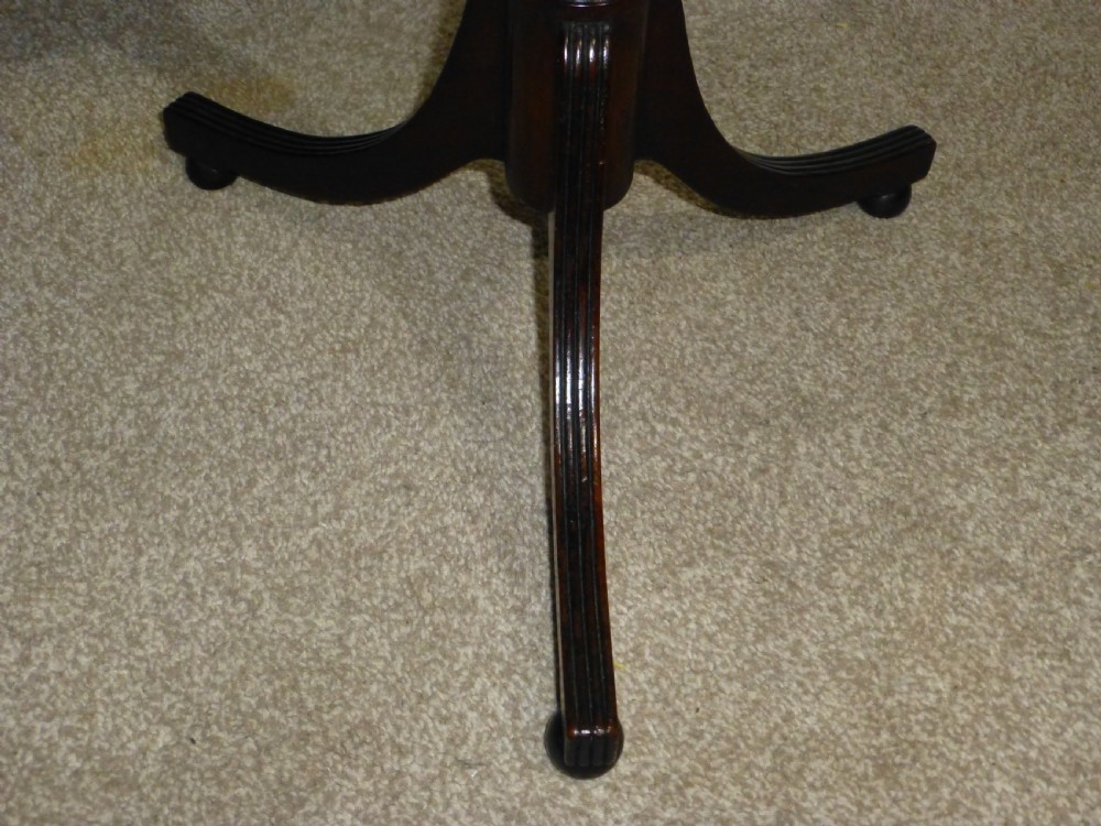 A Regency mahogany circular wine table featuring a moulded rim, a turned reeded pedestal, and three swept tripod legs. View II
