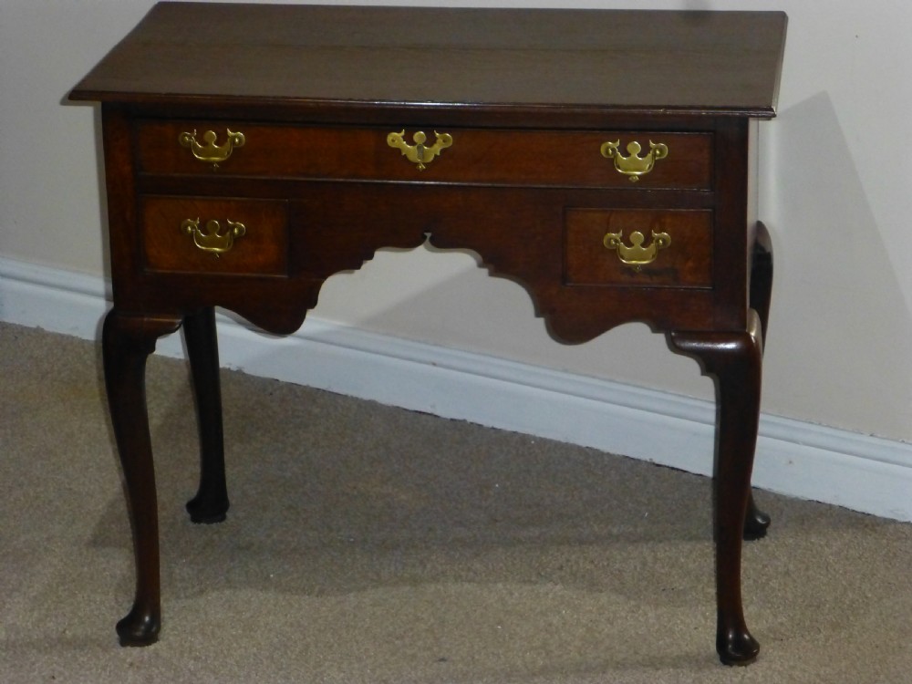 An 18th-century Georgian mahogany lowboy table featuring cabriole legs, brass batwing drawer pulls, and a shaped apron.