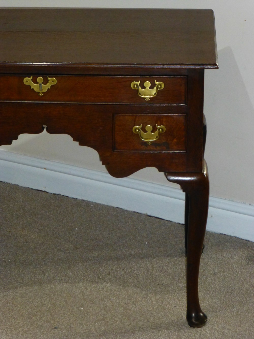 An 18th-century Georgian mahogany lowboy table featuring cabriole legs, brass batwing drawer pulls, and a shaped apron. View V