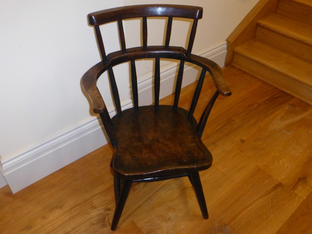 An 18th-century Welsh primitive stick Windsor armchair crafted from dark burr elm and ash with a comb back and turned legs.
