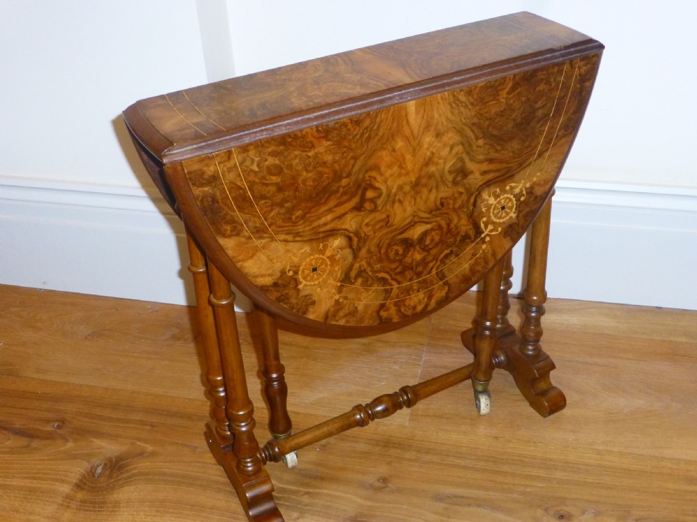 A 19th-century burr walnut Sutherland side table featuring drop leaves with floral marquetry inlay and turned legs on ceramic castors.