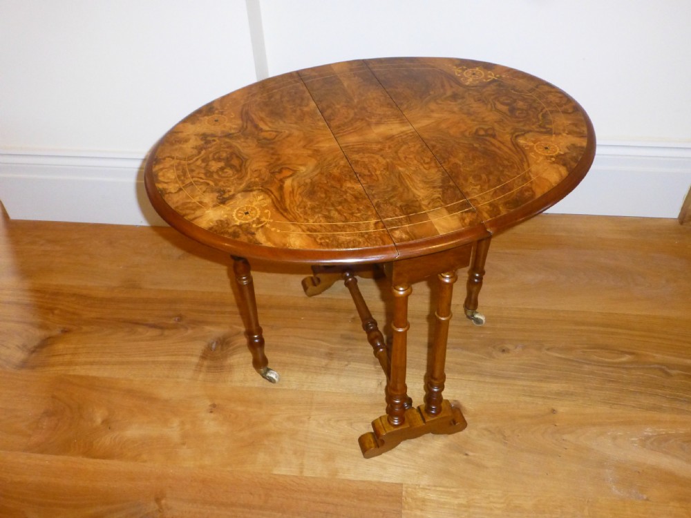 A 19th-century burr walnut Sutherland side table featuring drop leaves with floral marquetry inlay and turned legs on ceramic castors. View II