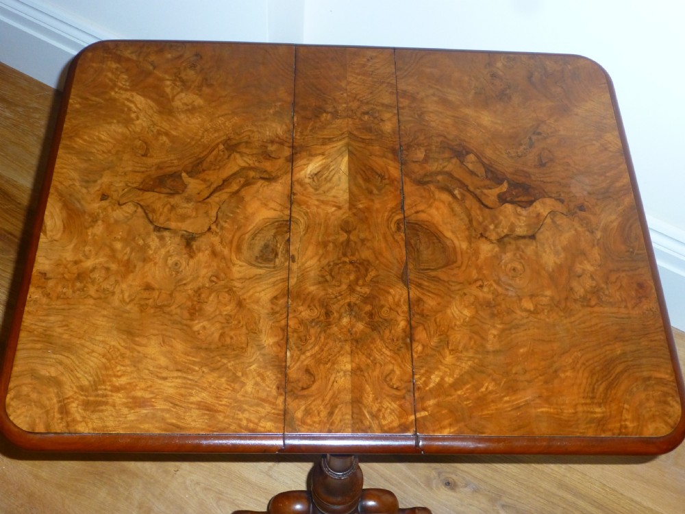 A Victorian burr walnut Sutherland table featuring two drop leaves, turned supports, carved trestle feet, and brass castors. View II