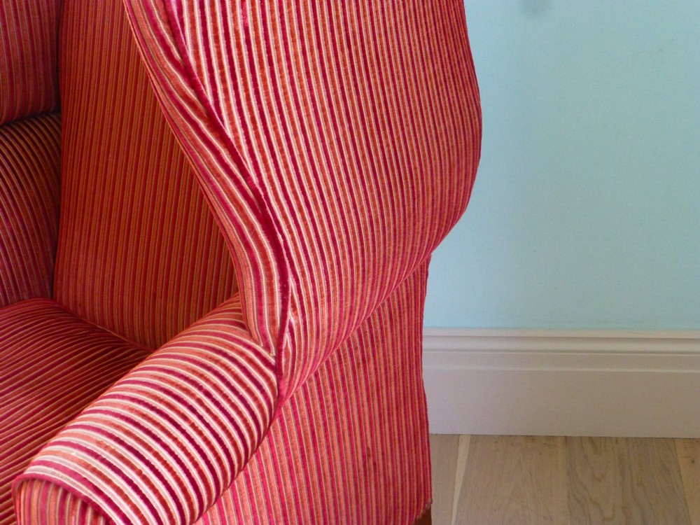 An 18th-century Georgian wingback armchair upholstered in red and gold striped fabric with carved cabriole front legs. View V