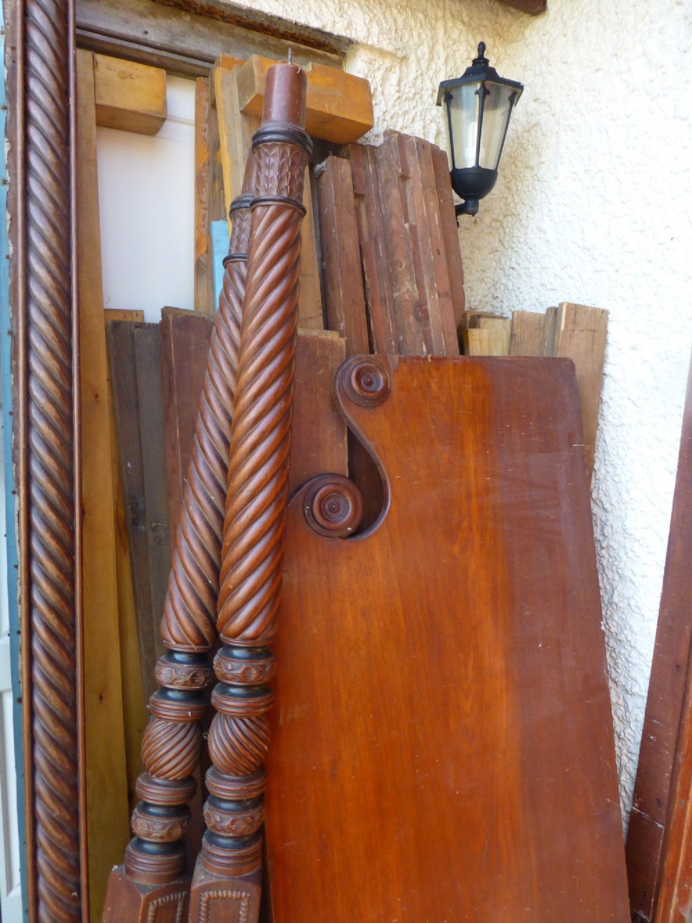 Dismantled components of a wooden four poster bed, including spiral-carved posts, reeded rails, and a shaped mahogany headboard. View II