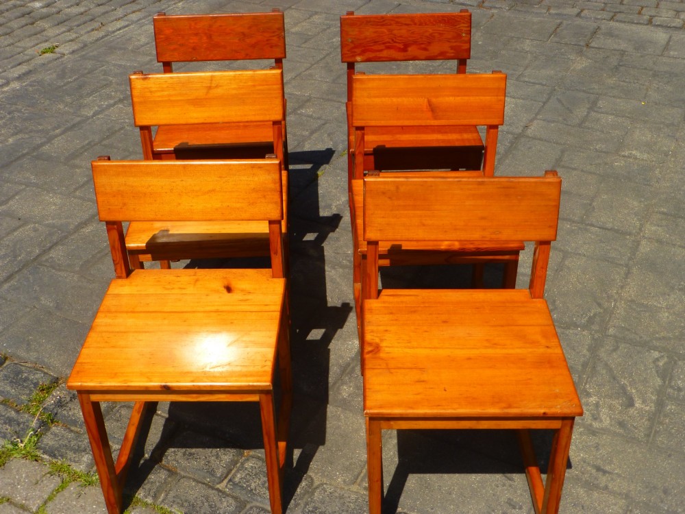 A set of six warm amber-toned solid pine dining chairs featuring flat rectangular backrests and solid square panel seats.