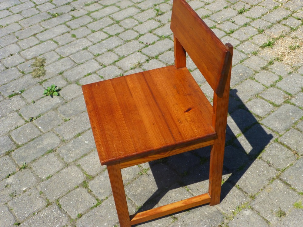A set of six warm amber-toned solid pine dining chairs featuring flat rectangular backrests and solid square panel seats. View III