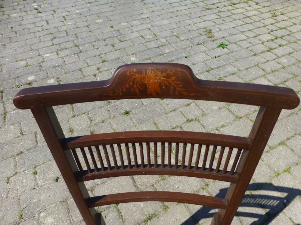 A set of four dark mahogany Edwardian dining chairs featuring decorative crest rail inlay and terracotta velvet seats. View II