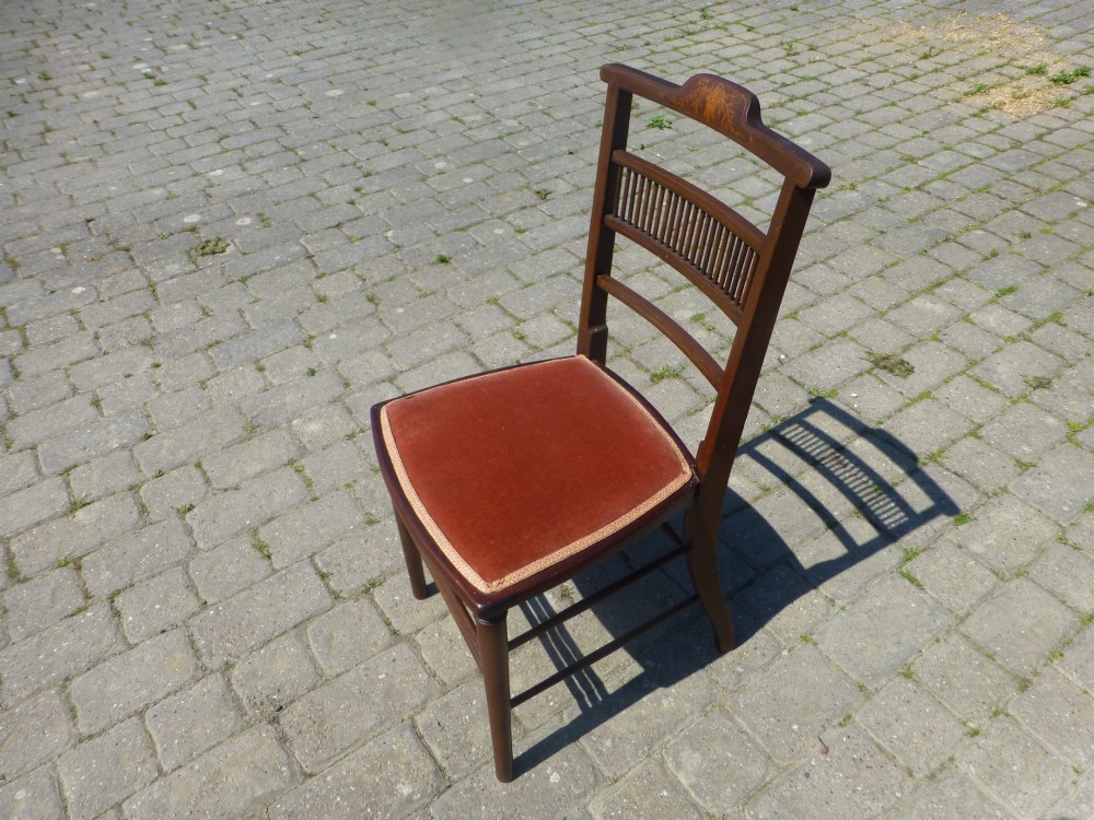 A set of four dark mahogany Edwardian dining chairs featuring decorative crest rail inlay and terracotta velvet seats. View IV