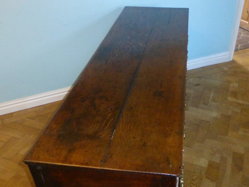 An 18th-century dark oak Georgian dresser base featuring three drawers with pierced brass handles and front cabriole legs. View III