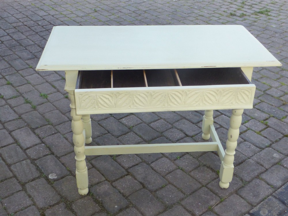 A late 19th-century cream-painted oak console table with a carved single drawer and turned legs connected by a low stretcher.