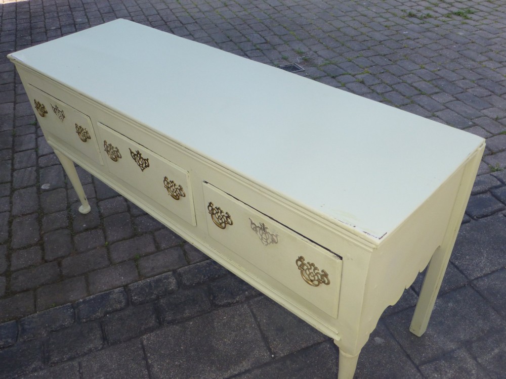 An 18th-century Georgian painted oak dresser base featuring three drawers with decorative brass handles, supported by slender legs with shaped side aprons. View II